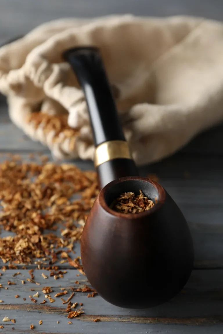 Pipe tobacco inside a wooden smoking pipe on a pouch.